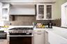 Kitchen with range with two ovens, extractor fan, glass insert cabinets, decorative backsplash, and white cabinetry