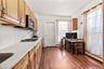 Kitchen featuring baseboard heating, dark wood-type flooring, light stone counters, and brown cabinetry