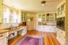 Kitchen with glass insert cabinets, white cabinets, and light wood-style flooring