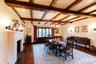 Dining area with a fireplace, dark wood finished floors, beamed ceiling, and a chandelier