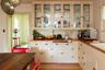 Kitchen with glass insert cabinets, light wood-style floors, white cabinets, and wood counters