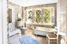 Bathroom featuring wallpapered walls, a freestanding bath, toilet, and wood finished floors