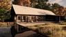 Rear view of house with a patio, a metal roof, and view of wooded area
