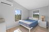 Bedroom with an AC wall unit, vaulted ceiling, light wood finished floors, and multiple windows