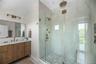 Bathroom with a marble finish shower, vanity, and light tile patterned floors