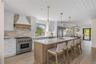 Kitchen with high quality appliances, wooden ceiling, decorative backsplash, a kitchen breakfast bar, and a kitchen island