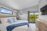 Bedroom with vaulted ceiling, light wood finished floors, a wall mounted AC, and access to outside