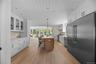Kitchen with backsplash, premium appliances, wooden ceiling, glass insert cabinets, and open floor plan