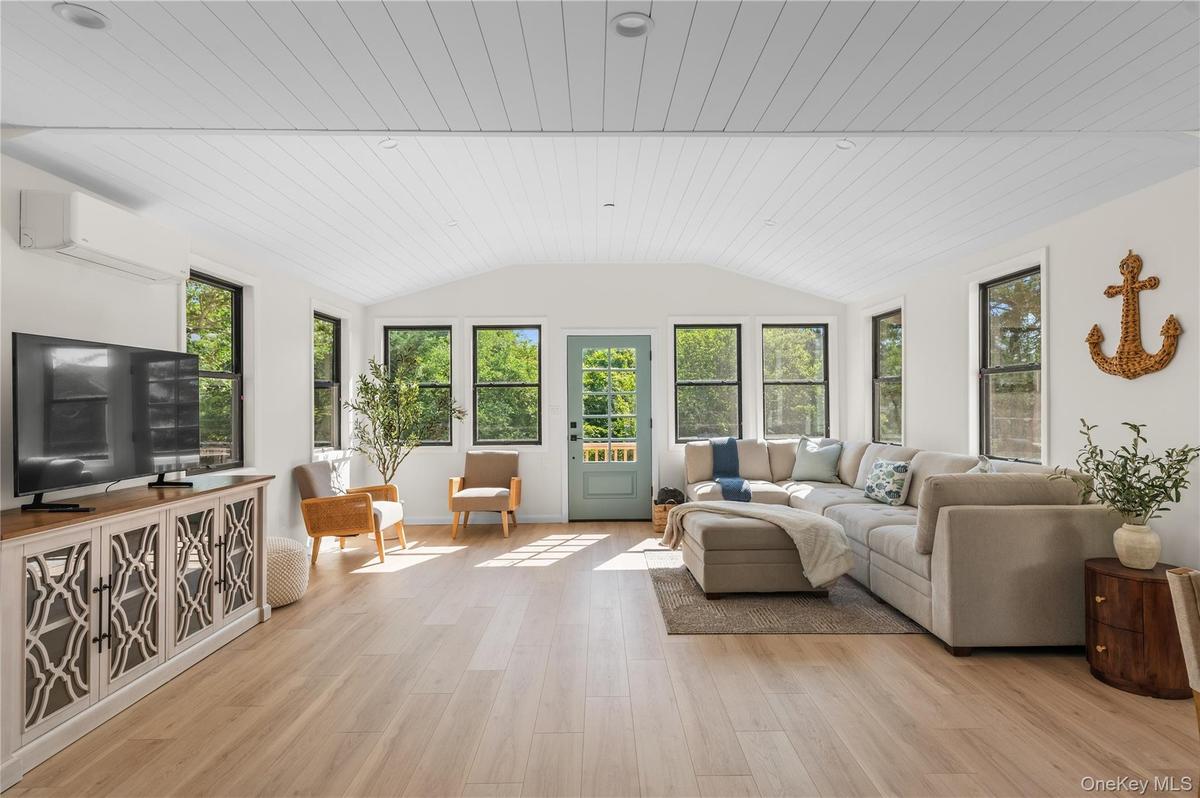 Sunroom with plenty of natural light, a wall unit AC, and lofted ceiling
