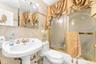 Full bathroom featuring toilet, sink, combined bath / shower with glass door, tile walls, and decorative backsplash