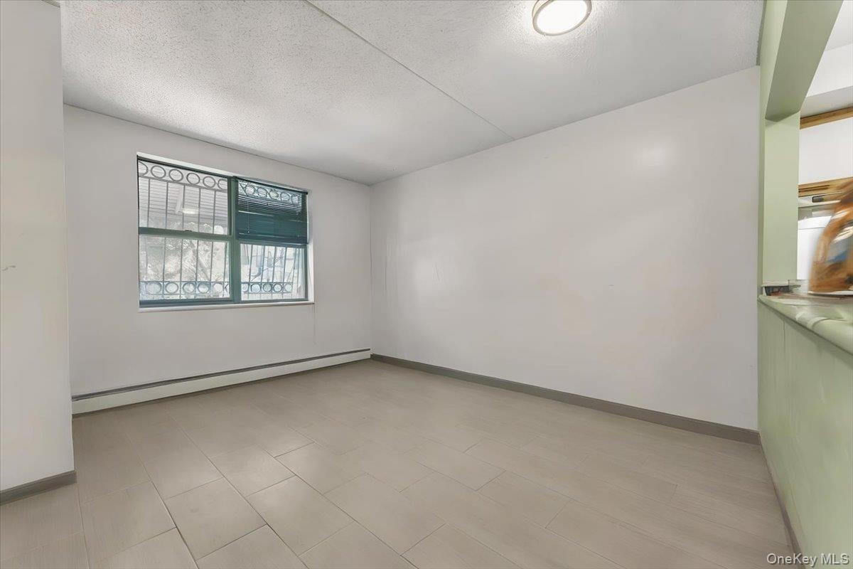 Empty room featuring baseboard heating and a textured ceiling