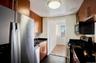Kitchen with stainless steel appliances, brown cabinetry, dark countertops, and dark tile patterned flooring