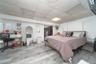Bedroom featuring a drop ceiling, an office area, light wood-style floors, and a spacious closet