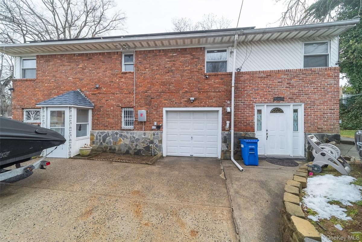 Rear view of property with a garage, driveway, and brick siding