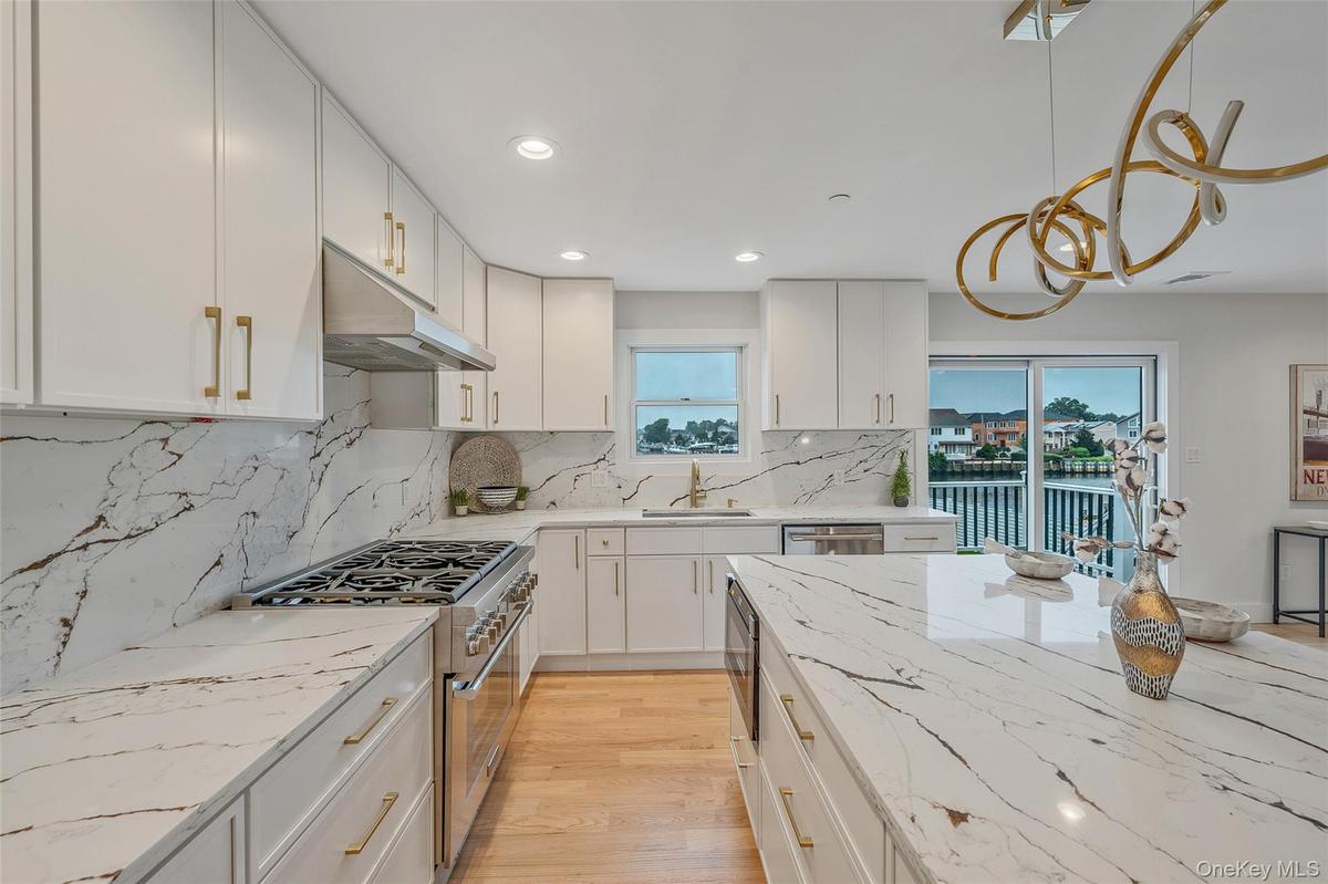 Kitchen featuring stainless steel appliances, under cabinet range hood, plenty of natural light, white cabinets, and recessed lighting