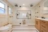 Bathroom featuring vanity, a marble finish shower, and tile walls