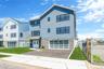 Multi unit property featuring stone siding, driveway, and an attached garage