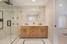 Bathroom featuring a marble finish shower, double vanity, and recessed lighting