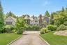 Elegant Tudor-style estate set on beautifully landscaped grounds featuring stone and half-timber architecture, a charming ivy-covered turret, and stat