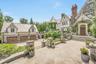 Stunning Tudor-style estate featuring stone and half-timber architecture, an ivy-covered turret, and a spacious motor court with a three car garage. T