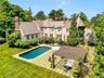 Resort-Style backyard featuring a geometric pool and expansive stone lounging terraces. Anchored by a bespoke architectural pergola and framed by matu
