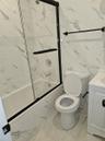 Full bathroom featuring vanity, shower / bath combination, tile walls, toilet, and marble finish floor