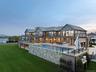 Back of property at dusk with a balcony, a yard, an outdoor living space, an outdoor pool, and a patio area