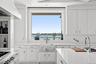 Kitchen featuring a sink, white cabinetry, wall chimney exhaust hood, a water view, and range