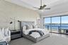 Bedroom featuring access to outside, a water view, vaulted ceiling, wallpapered walls, and a ceiling fan