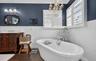 Bathroom featuring vanity, crown molding, a wainscoted wall, dark wood finished floors, and a soaking tub