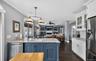 Dual tone kitchen featuring a peninsula, stainless steel appliances, open floor plan, ornamental molding, and light stone countertops