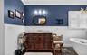 Full bathroom with vanity, a soaking tub, crown molding, dark wood-type flooring, and a wainscoted wall