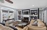 Living room with crown molding, a fireplace with flush hearth, wood finished floors, and recessed lighting
