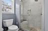 Bathroom featuring toilet and a marble finish shower