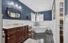 Bathroom featuring vanity, dark wood-style floors, ornamental molding, a freestanding bath, and a wainscoted wall