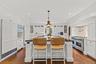 Gourmet chef’s kitchen with custom white cabinetry, premium stainless steel appliances, and an oversized island with seating. Elegant finishes, warm h