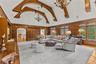 Living area featuring hanging chandeliers, a high ceiling, arched walkways, built in shelves, and rich wood paneled walls.