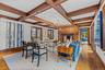 Living room with light wood-oak flooring, a fireplace, coffered ceiling, and suspended lighting.