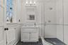 Full bath featuring vanity, a stall shower, wainscoting, tile walls, and detailed molding.