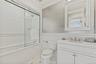 Full bath with vanity, tiled shower / bath, a wainscoted wall, tile walls, and crown molding.