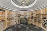 A collector’s sanctuary, this climate-controlled circular wine rotunda features floor-to-ceiling natural wood racking and elegant slate herringbone fl