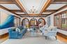 Stunning living room showcasing timeless architectural detail with a coffered ceiling, rich wood trim, elegant chandelier, and beautiful arched doorwa
