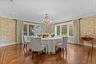 Elegant formal dining room featuring a stunning crystal chandelier, patterned wallpaper, and beautiful herringbone hardwood floors. Expansive windows 