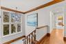 Corridor featuring arched walkways, crown molding, light wood-style floors, and chandelier.