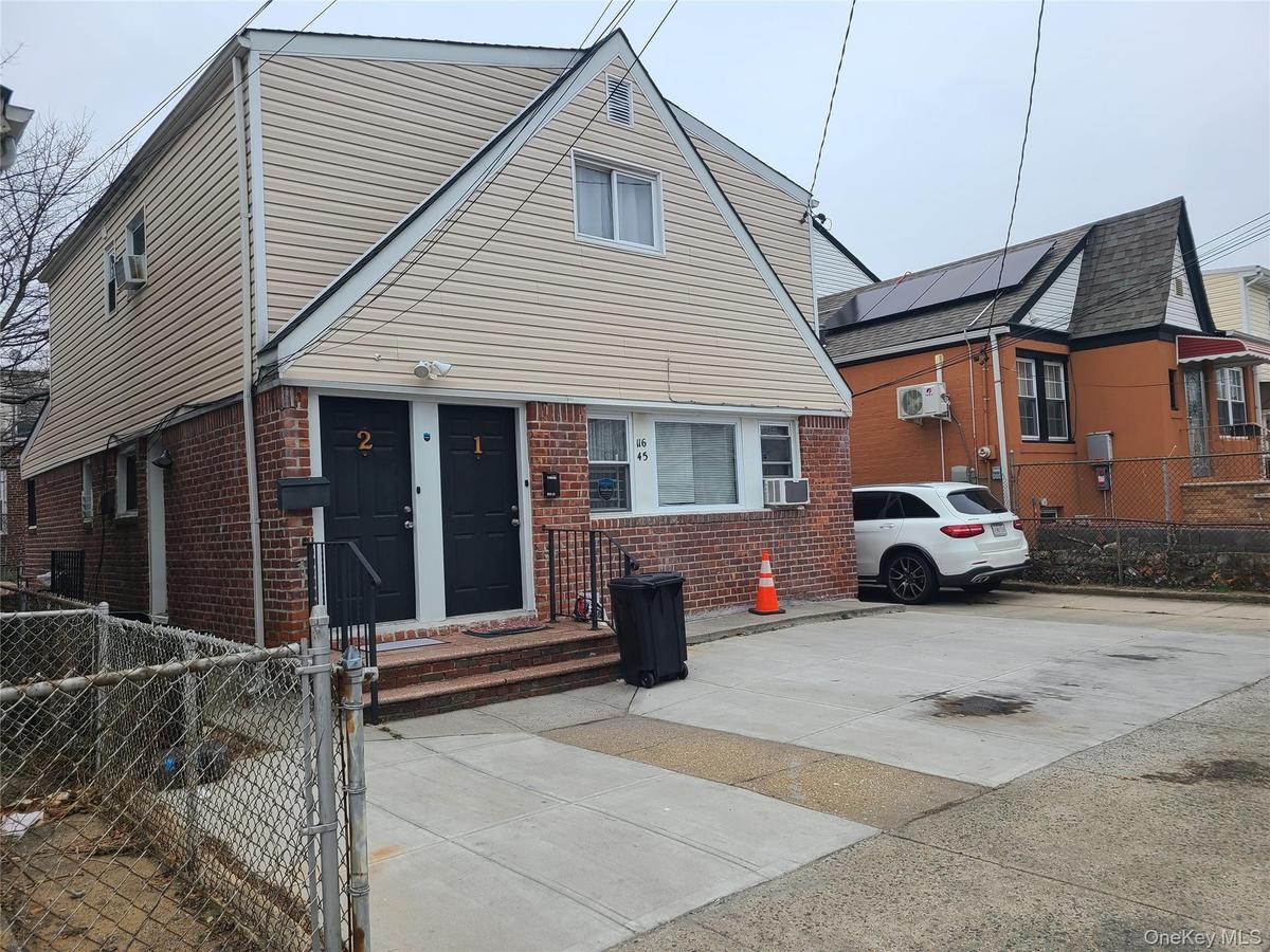View of front of house with cooling unit, brick siding, and fence private yard