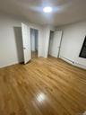 Unfurnished bedroom with a baseboard heating unit, light wood-style floors, and a closet