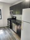 Kitchen with stainless steel appliances, dark countertops, light wood-type flooring, modern cabinets, and dark cabinets