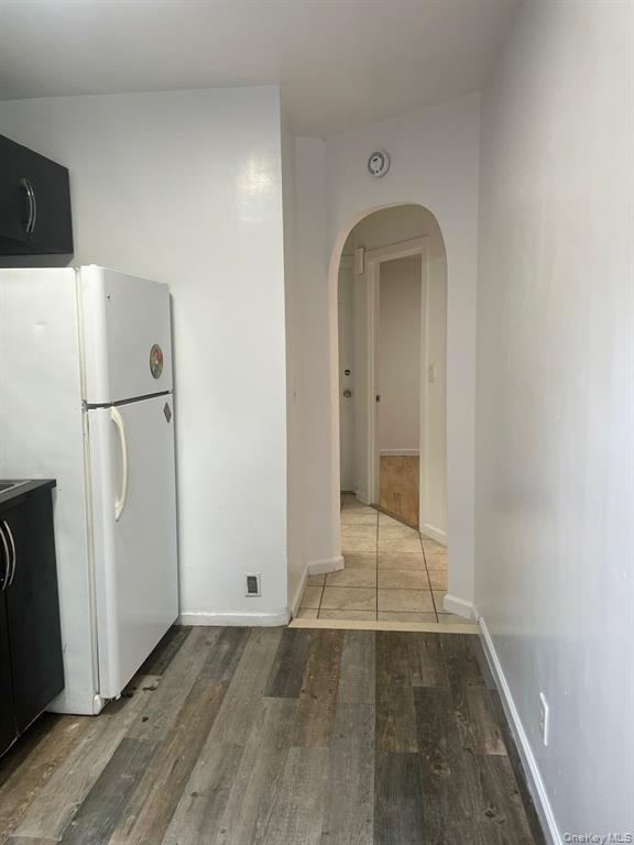 Kitchen with freestanding refrigerator, light wood-style floors, and arched walkways