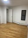 Unfurnished bedroom with a baseboard radiator, light wood finished floors, and a spacious closet