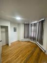 Unfurnished bedroom featuring light wood-style floors, a closet, electric panel, and a baseboard heating unit